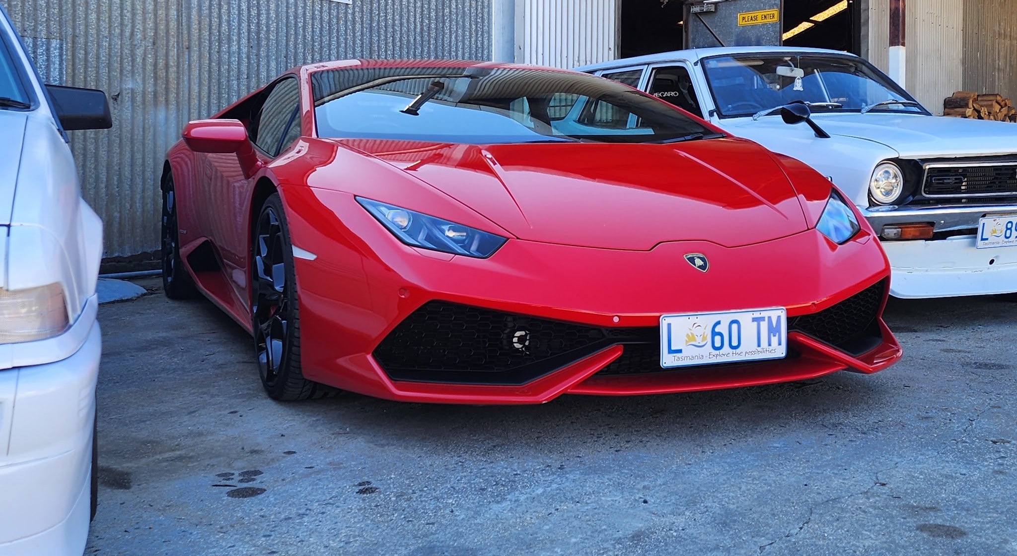 A red Lamborghini Huracan parked outside the workshop sheds